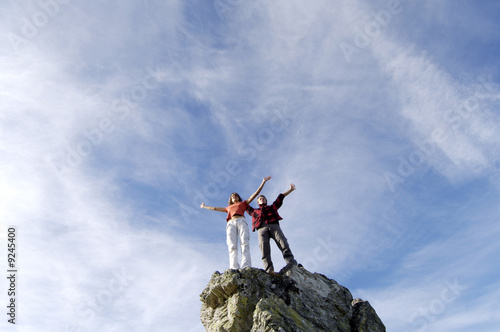 Photo: Junges Paar stehen auf Berggipfel, die Arme ausstrecken, Junges Paar stehen auf Berggipfel, die Arme ausstrecken,