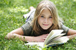 Girl (13-14) lying on grass reading, smiling