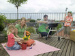 Family on balcony, father preparing barbecue