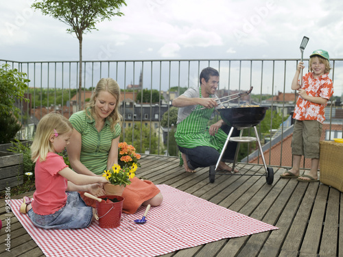 Photo: Familie auf dem Balkon, der Vater, der Grill vorbereiten Familie auf dem Balkon, der Vater, der Grill vorbereiten