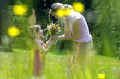 Mother passing bouquet to daughter (6-7) in meadow, side view