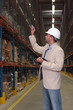 supervisor in hardhat counting stocks in warehouse