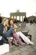 Two young woman with shopping bags sitting on pavement