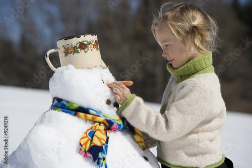 Photo: Österreich, Mädchen Karotte auf Schneemann Gesicht, Lächeln, Portrait Österreich, Mädchen Karotte auf Schneemann Gesicht, Lächeln, Portrait