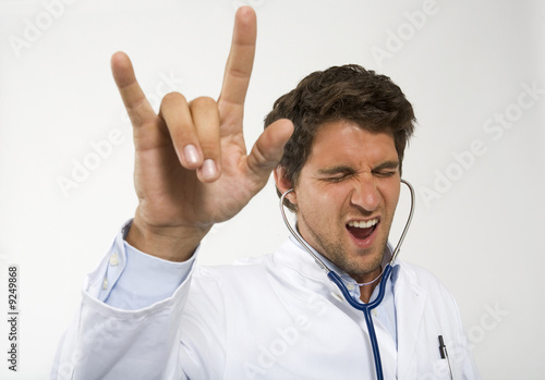 Photo: Male doctor dancing with stethoscope in ear, close-up Male doctor dancing with stethoscope in ear, close-up