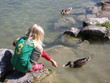 mädchen füttern enten im see