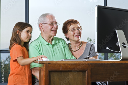 Foto: grandparents and granddaughter with computer at home grandparents and granddaughter with computer at home
