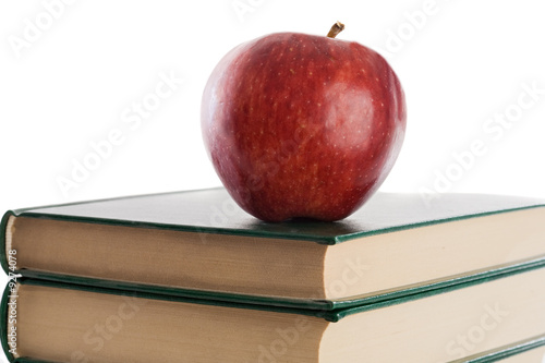 Photo: A red apple on top of books on a white background A red apple on top of books on a white background