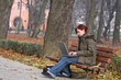 Young woman working on a laptop in a park in autumn.