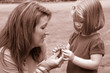 small child takes flower from mother