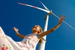 child playing with the wind near a wind turbine