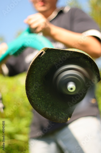Photo: Man is holding a lawn mower which is on Man is holding a lawn mower which is on
