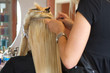 Image of a hairdresser applying extensions to a client's hair