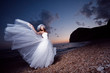 Bride posing showing her wedding dress on sunset beach