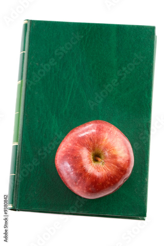 Photo: Apple red on a green book seen from above isolated Apple red on a green book seen from above isolated