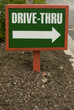 Green and white plastic drive-thru sign in the ground