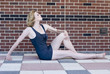 Lovely blond woman on the ground with knee up against brick Lovely blond woman on the ground with knee up against brick