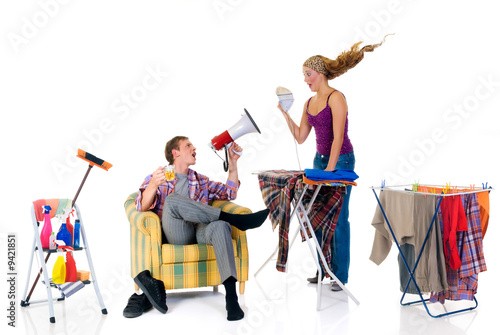 Photo: Young bossy man with megaphone, woman ironing clothing Young bossy man with megaphone, woman ironing clothing