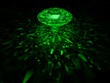 A sparkling green brilliant cut diamond on dark background