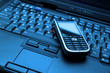 Blue-toned keyboard of laptop and modern smartphone on it. Blue-toned keyboard of laptop and modern smartphone on it.