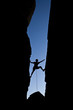 Rock climber silhouetted as he climbs up a chimney.