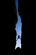 Rock climber silhouetted as he climbs up a chimney.