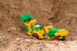 yellow toy bulldozer with the trailer on a heap of sand