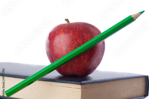 Photo: A red apple with green pencil on top of many books isolated A red apple with green pencil on top of many books isolated