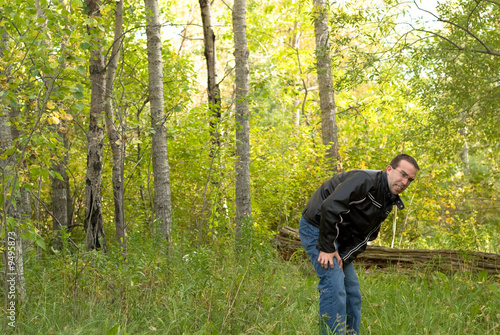 Photo: A man coming out of the bush scratching himself A man coming out of the bush scratching himself