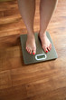A woman standing on scales on a wooden bathroom floor