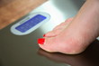 A woman standing on scales on a wooden bathroom floor