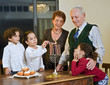 grandperents and grandchildren lightening Hanukkiyah together