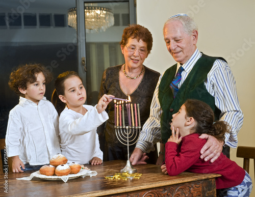 grandperents and grandchildren lightening Hanukkiyah together