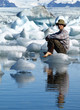 Man, sitting on ice in Jokulsarlon lagoon, Iceland