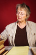 Mature woman with old books takes notes in notepad