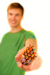 guy suggests and holds  set of color pencils in  hand
