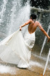 Beautiful young bride playing in a waterfall on her wedding day.