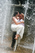 Bride and groom under a water fountain on their wedding day.
