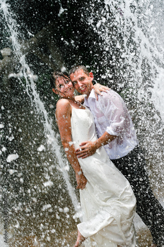 Bride and groom under a water fountain on their wedding day.