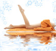 long legs of relaxed lady with orange towel on white sand