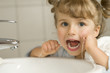 Cute girl cleaning teeth by floss in bathroom