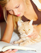 Young beautiful woman with a cat reading a book
