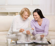 Adult mother and daughter enjoying photo album in livingroom