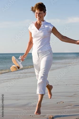 Active and happy senior woman running at the beach