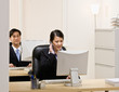 Businesswoman talking on headset and working at computer