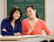 Student with text books doing homework with friend in school
