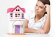 Miniature toy house with dreaming woman looking at it