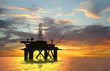 Oil rig silhouette over orange sky