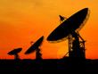 Three satelite dishes over sunset