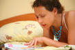 Young woman reads on bed